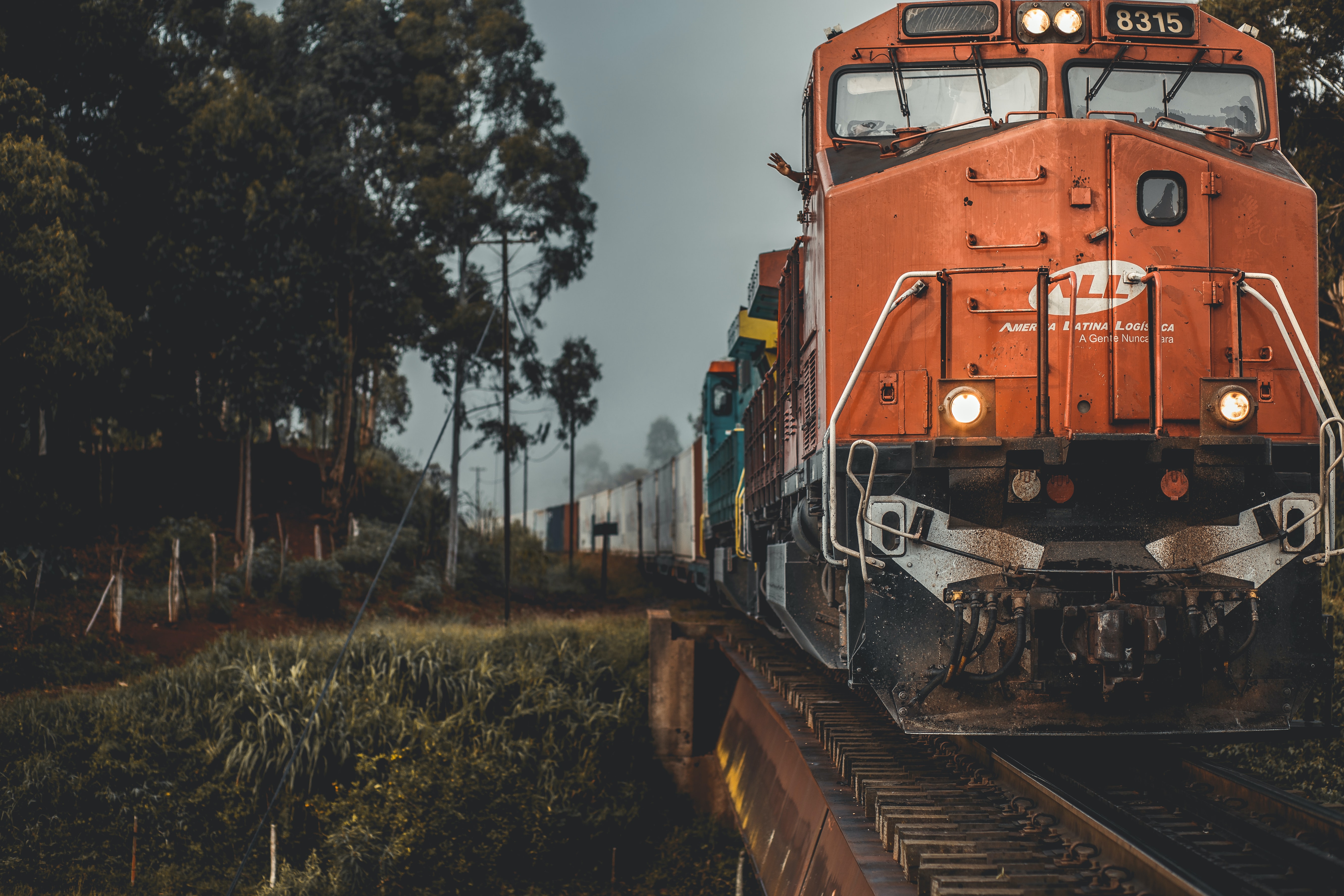 Orange cargo freight train passing through green scenery